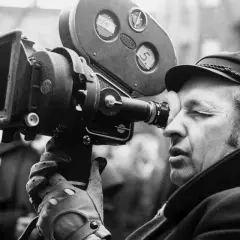 Andrzej Wajda patrzy przez wizjer kamery filmowej.