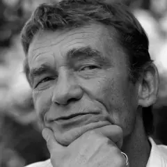 Portret Krzysztofa Kiersznowskiego z dłonią pod brodą, w tle rozmyte liście.