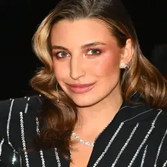 Elegancka aktorka w błyszczącej marynarce, zastanawiająca się, ile zarabia aktorka w Polsce.
