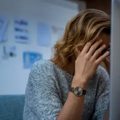 Zmęczona osoba z ręką na czole przed komputerem. Taki stres, to nie ze mną.