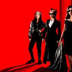 Grupa eleganckich kobiet, gwiazd filmu Ocean's 8, pozuje na czerwonym tle.