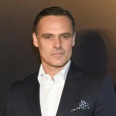 Jan Wieczorkowski, znany z imponującego wzrostu, w eleganckim garniturze i białej koszuli z granatową poszetką w kropki.