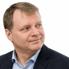 Uśmiechnięty Jacek Sobala w granatowej marynarce i błękitnej koszuli, patrzący w bok.
