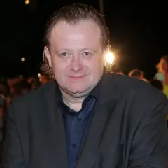 Grzegorz Warchoł w garniturze, na tle tłumu.