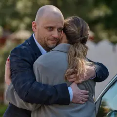 Mężczyzna obejmuje kobietę, patrząc wprost w obiektyw. Czy ukryta prawda dalej jest nagrywana w tym spojrzeniu?