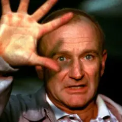 Robin Williams, który zdobył Oscara za rolę w "Buntowniku z wyboru", z dłonią przed twarzą.