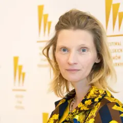 Agata Buzek, znana z imponującego wzrostu, w barwnej stylizacji z błyszczącymi akcentami na twarzy.