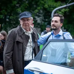 Stars serialu "Dzielnica strachu" obsada: starszy mężczyzna w czapce i płaszczu oraz młodszy w niebieskiej koszuli przy radiowozie.