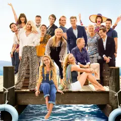 Obsada filmu "Mamma Mia!" na drewnianym molo z widokiem na morze.