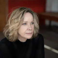 Portret Ann Kathrin Kramer z niebieskimi oczami i blond włosami, w czarnej bluzce, zamyślona.