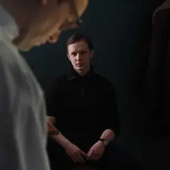 Filip Pławiak siedzi w ciemnym pomieszczeniu, wpatrując się wprost przed siebie.