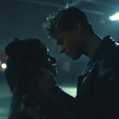 Nocna scena z filmu "The Kissing Booth". Elle i Noah w intymnym uścisku, w tle migoczące światła samochodów.
