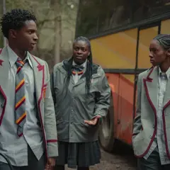 Kedar Williams Stirling i dwaj koledzy w szkolnych mundurkach stoją obok autobusu.