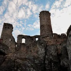 Ruiny zamku na skale pod błękitnym niebem z chmurami.
