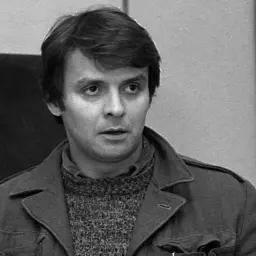 Krzysztof Kołbasiuk w studiu nagraniowym, z mikrofonem przed twarzą.