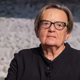 Portret Agnieszki Holland w okularach, w czarnej bluzce.