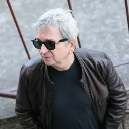 Juliusz Machulski w skórzanej kurtce i okularach przeciwsłonecznych, z siwymi włosami, wygląda jakby planował kolejny kultowy film.
