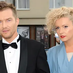 Antoni Sztaba w czarnym smokingu i jego towarzyszka w błękitnej kreacji na czerwonym dywanie.
