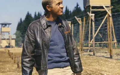 Steve McQueen w skórzanej kurtce, w tle obóz jeniecki.