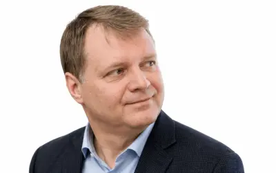 Uśmiechnięty Jacek Sobala w granatowej marynarce i błękitnej koszuli, patrzący w bok.