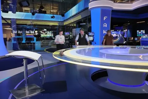 Trzy osoby stoją przy okrągłym stole w nowoczesnym tvn studio sękocin. W tle monitory i sprzęt.