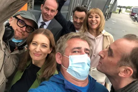 Uśmiechnięta usta usta obsada na planie zdjęciowym. Wszyscy w dobrych humorach, gotowi do pracy.