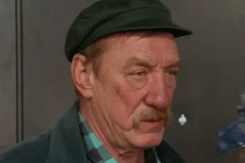 Sylwester Maciejewski w czapce i kurtce, z wąsem.