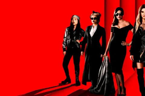 Grupa eleganckich kobiet, gwiazd filmu Ocean's 8, pozuje na czerwonym tle.