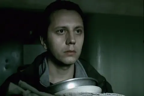 Młody mężczyzna z miską w rękach, jego spojrzenie sugeruje trudną sytuację. To jego job, ostatnia szara komórka obsada.