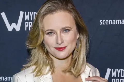 Marta Chodorowska, z błyszczącymi oczami i złotymi kolczykami, uśmiecha się do obiektywu na tle logo "Wydawnictwo".