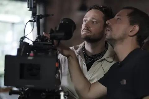 Dwóch mężczyzn przy profesjonalnej kamerze filmowej, jeden z nich reżyser Daniel Jaroszek.
