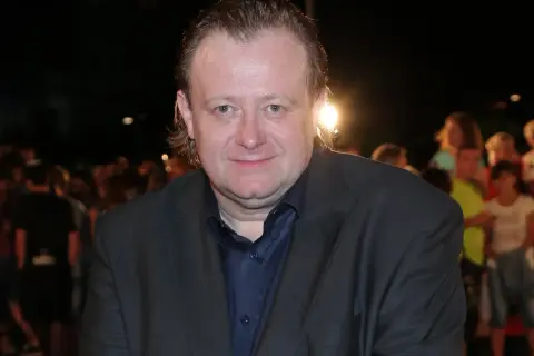 Grzegorz Warchoł w garniturze, na tle tłumu.