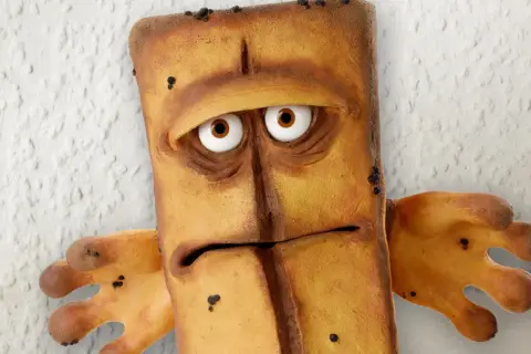 Smutny Bernd das Brot, z wielkimi oczami i wyrazem twarzy pełnym zmartwienia, stoi na tle chropowatej ściany.