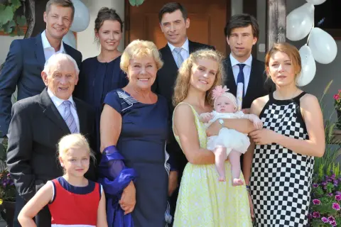 Rodzina z serialu "M jak miłość" pozuje do zdjęcia. Wszyscy uśmiechnięci, w tle balony i kwiaty.