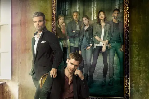 Grupowe zdjęcie obsady "The Originals" w stylizowanych strojach. W pierwszym planie siedzi Klaus, a za nim stoi Elijah. W tle, w ramie obrazu, widać pozostałych członków rodziny.