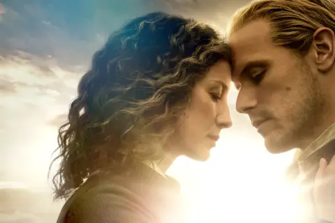 Claire i Jamie, bohaterowie serialu Outlander, z czołami dotykającymi się na tle nieba.
