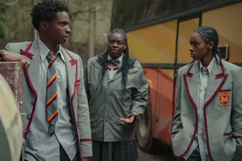 Kedar Williams Stirling i dwaj koledzy w szkolnych mundurkach stoją obok autobusu.