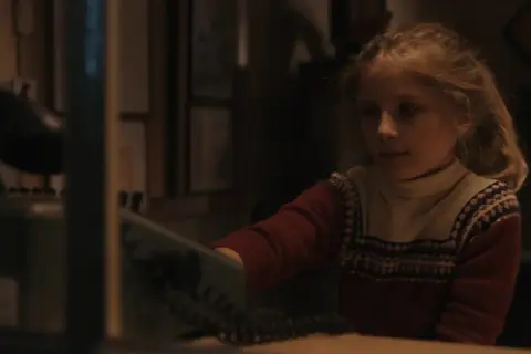 Młoda Carlotta von Falkenhayn sięga po słuchawkę telefonu, jej oczy błyszczą ciekawością.