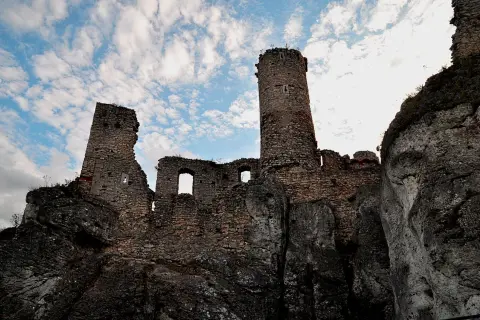 Ruiny zamku na skale pod błękitnym niebem z chmurami.