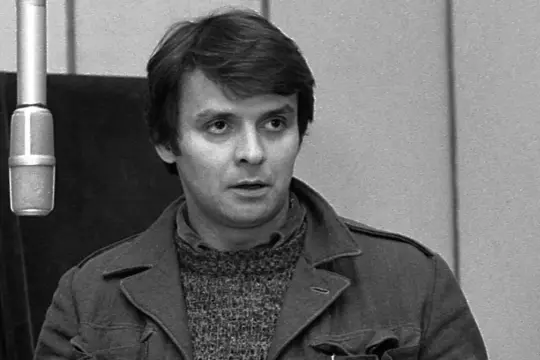 Krzysztof Kołbasiuk w studiu nagraniowym, z mikrofonem przed twarzą.
