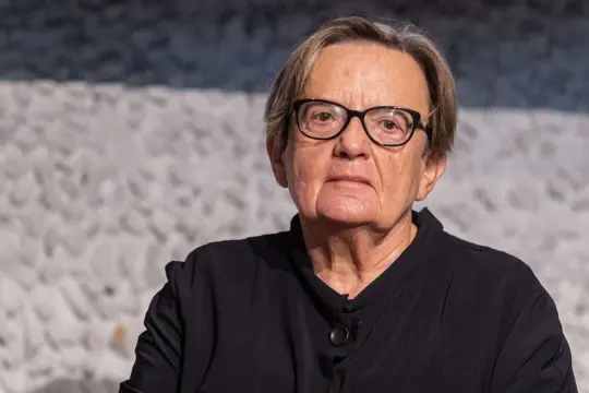 Portret Agnieszki Holland w okularach, w czarnej bluzce.