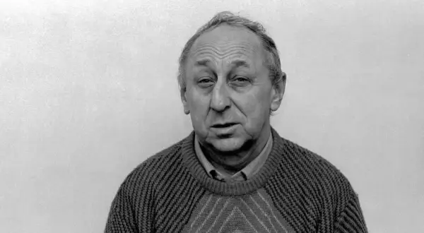 Portret Tadeusza Wojtycha w swetrze z geometrycznym wzorem. Jego twarz jest zmarszczona, a spojrzenie skierowane prosto w obiektyw.