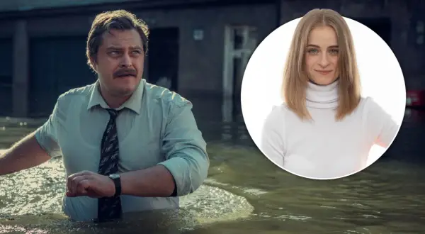 Mężczyzna w koszuli i krawacie brodzi w wodzie, obok uśmiechnięta kobieta w golfie. Wielka woda zalała miasto.