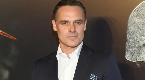 Jan Wieczorkowski, znany z imponującego wzrostu, w eleganckim garniturze i białej koszuli z granatową poszetką w kropki.