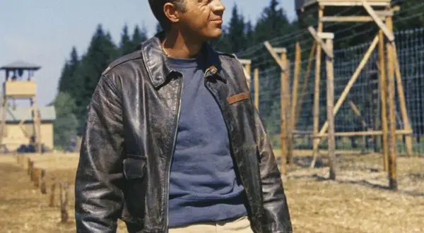 Steve McQueen w skórzanej kurtce, w tle obóz jeniecki.