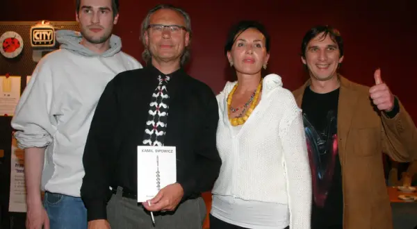 Szymon Sipowicz z książką "Kamil Sipowicz" w ręku, obok niego stoją inne osoby.