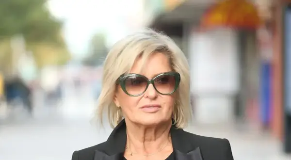 Ewa Kasprzyk w okularach przeciwsłonecznych i czarnej marynarce, z blond włosami i delikatnym makijażem.