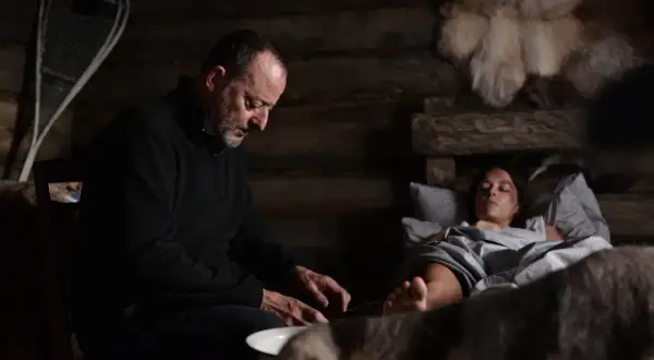 Jean Reno w "Cold Blood Legacy" obsada: mężczyzna pochyla się nad ranną kobietą w chatce.