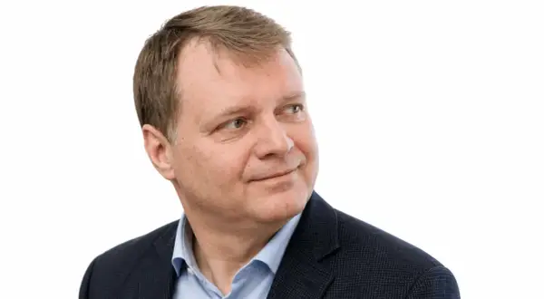Uśmiechnięty Jacek Sobala w granatowej marynarce i błękitnej koszuli, patrzący w bok.