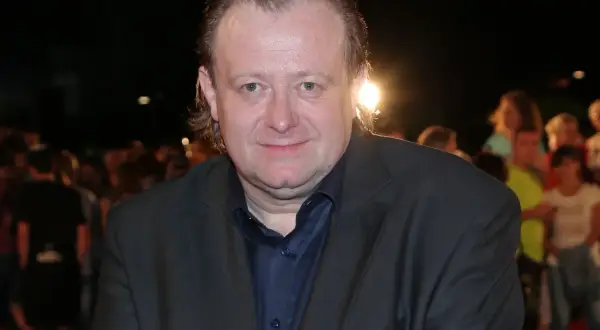 Grzegorz Warchoł w garniturze, na tle tłumu.
